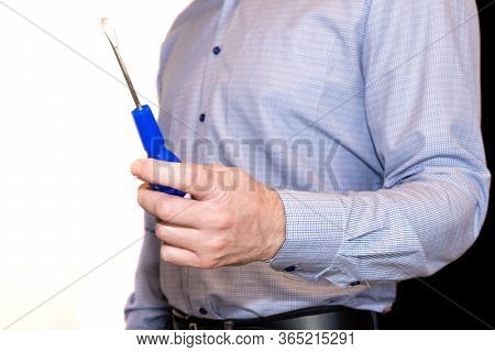 The Man Inside The Apartment Holds A Blue Screwdriver In His Hand.