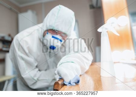 Coronavirus Pandemic. A Disinfector In A Protective Suit And Mask Sprays Disinfectants In House Or O