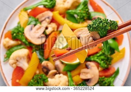 Pad Pak Ruam Or Veg Thai Stir-fried Vegetables Close Up Slices In Chopsticks . Pad Pak Is Thailand C