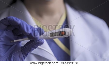 High Body Temperature On Electronic Thermometer In Medics Hand. Doctor Warning About Infection Showi