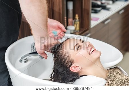 Hands Of Barber Are Washing The Woman Hair In The Beauty Salon. Girl Is Laughing While Washing Her H