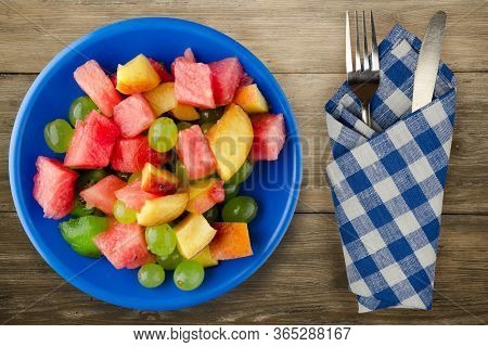 Fruit Salad On A Brown Wooden Background. Vegetarian Salad Of Fruit On A Blue Plate With Fork Ank Kn