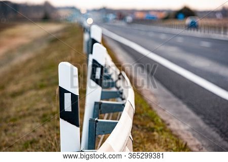 Black And White Signal Road Posts On An Asphalt Road. Country Road And Fence.