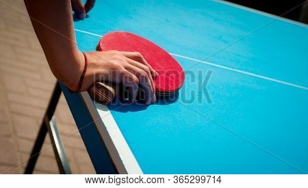 Red Tennis Racket In The Hand. Blue Table For Sports Games. Summer Fun. Excitement.