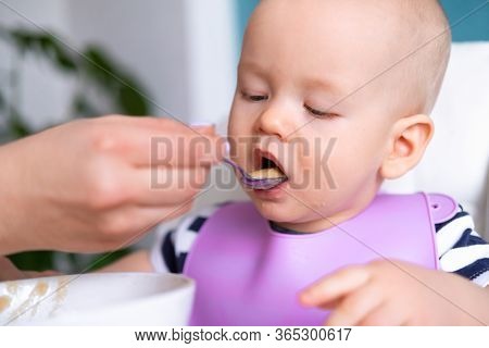 Baby Food. Mom Feeds Little Caucasian Child. Healthy Porridge, Mother Hands With Spoon. Newborn Infa
