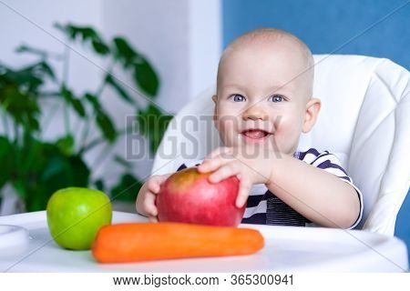 Baby Food. Little Smiling Caucasian Child With Big Red Apple And Carrot On Highchair. Healthy Food. 