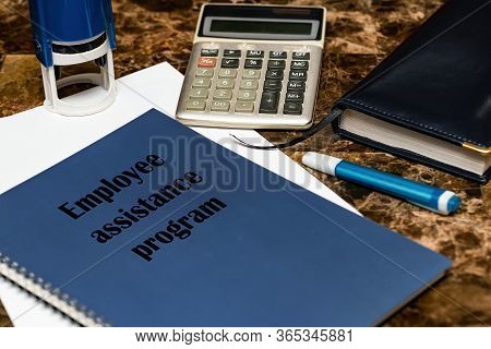 The Eap Employee Assistance Program Is Written On A Blue Book Lying On A Marble Desk In The Office A