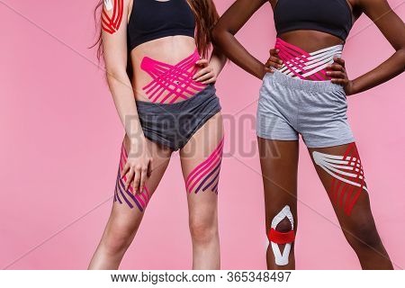 Kinesiology Taping. Two Young Female Athletes On Pink Background With Kinesiology Tape On Neck, Shou