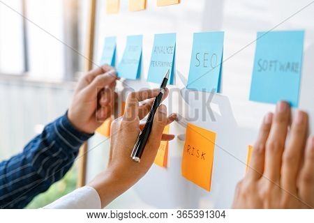 Young Business Workers Posting With Sticky Notes Stickers Reminders  Creative Brainstorming At Board