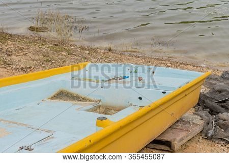 Aft Section Of Small Yellow Metal Fishing Boat On Shore Of River.