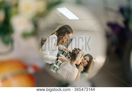 Two Professional Female Make-up Artist Doing Makeover In Lighting Dressing Room, View From Afar. Con