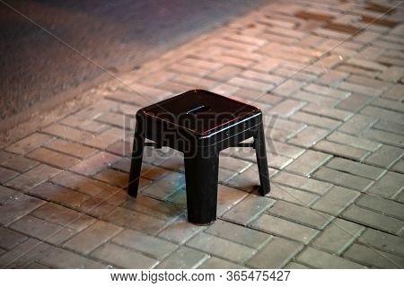 The Black Metal Stool Is Near Street Restaurant On The Ground. The Small Chair Stands On The Sidewal