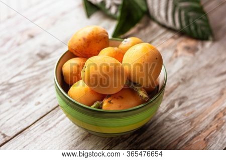 Ripe Medlar Fruit (eriobotrya Japonica) And Green Medlar Leaves On Wooden Table.