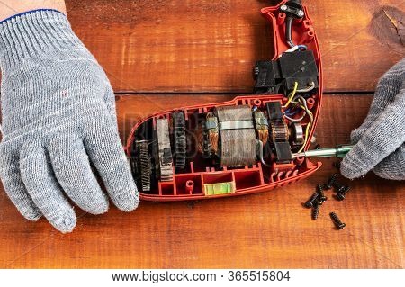 Technician Repairs Old Electric Drill On Brown Wooden Table