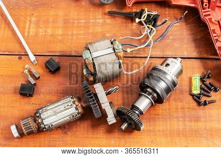 Technician Repairs Old Electric Drill On Brown Wooden Table