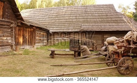 Log Cabin And Rural Wooden Trolleys. Very Steep Roofs Of Houses.