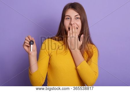 Studio Shot Of Happy Woman Celebrating Her Success, Wins New Car, Holding Key In Hand, Covering Mout