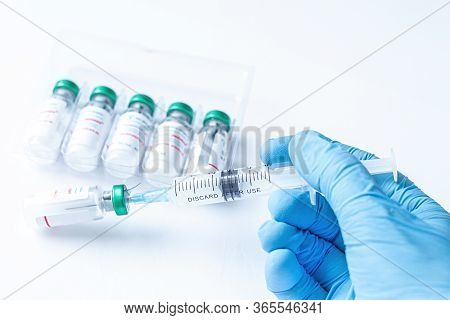 The Doctors Hand In A Medical Gloves Holds A Syringe With The Coronavirus, Covid-19, Ncov 2019 And F