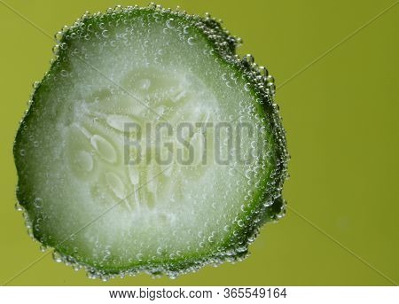 Beautiful Vegetable Background. One Slice Of Cucumber Closeup. Texture Of Cucumber Slices In Bubbles