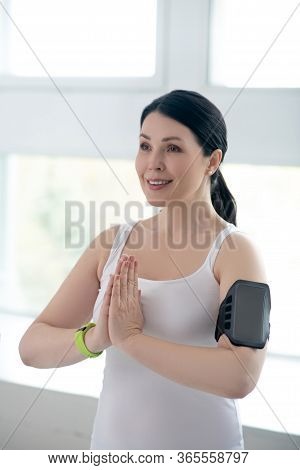 Brunette Female Performing Namaste, Pressing Hands Together, Wearing Pulsometer