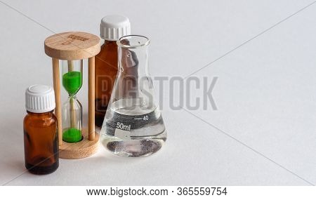 Hourglass, The Medical Bulb And The Medicine Bottles On A White Background. Place For The Label.