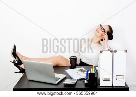 A Young Handsome Business Woman In Strict Clothes And Eyeglasses Cozily Threw Her Feet In Shoes On H