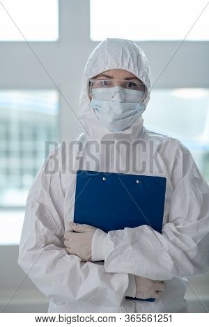 Medical Worker In Protective Clothing, Medical Mask And Goggles Holding Clip Folder