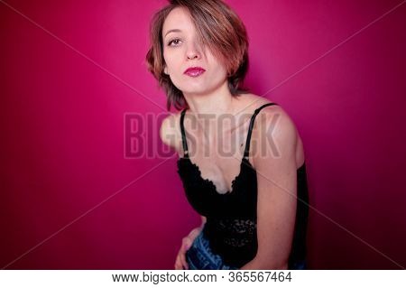 Young Woman With Short Hair Dressed In Black Lace Bustier And Blue Jeans Is Posing In The Studio On 
