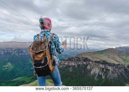 A Beautiful Girl Stands High In The Beautiful Mountains With A Compass In Her Hands. The Concept Of 