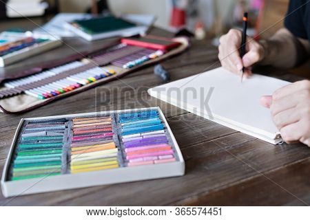 Man Painting With Pencil And Pastel Crayon Chalks On Paper. Box Of Pastel Chalks And Color Pencils O