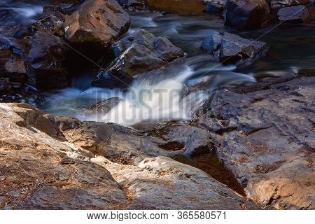 Water Intentionally Blurred By Slow Camera Shutter Speed Flowing Softly Over Rocks On A Creek Bed