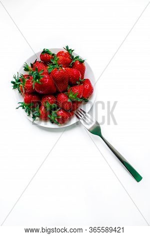 White Plate With Strawberries On A White Background, And A Fork.