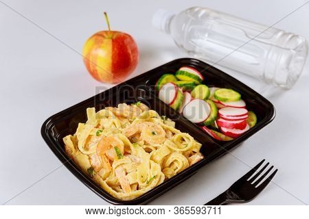 Black Plastic Container With Pasta, Shrips And Fresh Salad. Food Delivery.