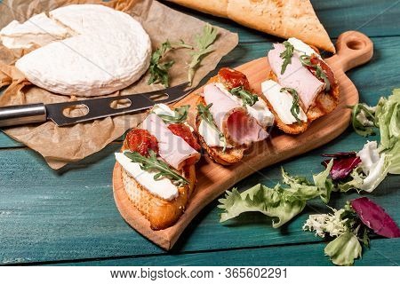 Appetizers Table With Italian Antipasti Snacks. Bruschetta With Brie Cheese, Arugula And Sun-dried T