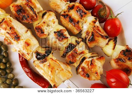 svinekød shish kebab på hvidt fad med grøntsager