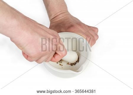 Pestle And Porcelain Kitchen Mortar In Hands During Spices Grinding On A White Backgroubd, Close-up 