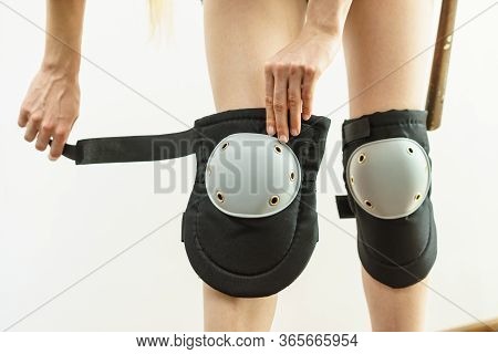 Unrecognizable Woman Wearing And Adjusting Her Safety Knee Protectors Pads. Safe Workwear During Con