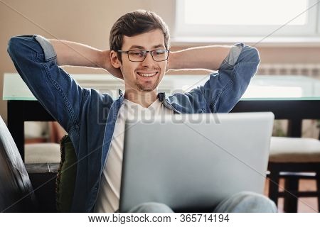 Happy Freelancer In Eyeglasses Using Laptop For Remote Work While Sitting On Sofa At Home, Feeling S