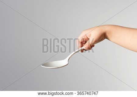 Child Hand Holding White Spoon In Right Hand Trying To Hold It In Right Way On The White Background