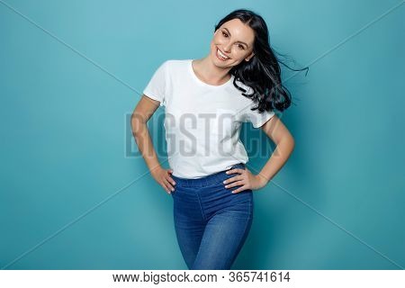 Young Woman In The Studio On A Blue Background Conveys Different Emotions. Beautiful Woman In Jeans 