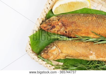 Grilled Fish In A Wicker Basket With Greens On A White Background. Isolate Creative Presentation And