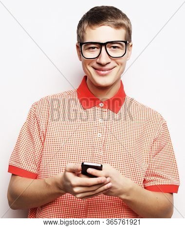 Happy young man in glasses typing sms on white background