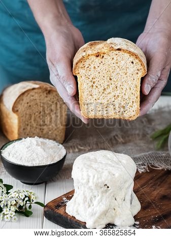 Female Hands Hold Half-baked Freshly Baked Bread, Sourdough And Baking Ingredients On A White Wooden