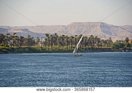 Traditional Egyptian Felluca River Boat Sailing On The Nile With Luxor West Bank In Background