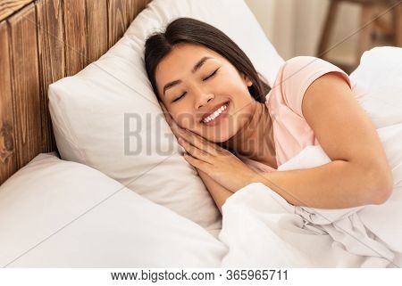 Wellslept Chinese Girl Sleeping Well In Cozy Bed In Bedroom At Home. Sweet Dreams Concept. Empty Spa
