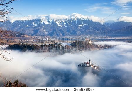 amazing panorama of Lake Bled Blejsko Jezero on a foggy morning with the Pilgrimage Church of the Assumption of Maria on a small island and Bled Castle and Julian Alps in backgroud