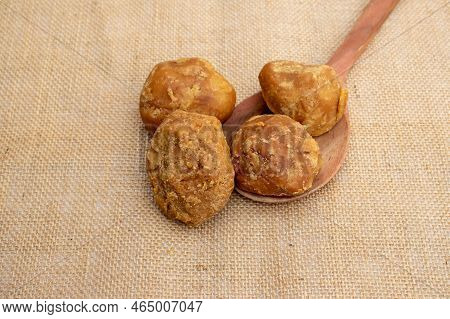 Closeup Of Organic Palm Jaggery Or Gur In A Wooden Ladle Isolated On Burlap Fabric