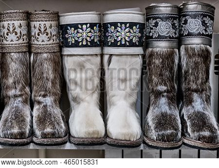 Three Pairs Of High Fur Boots On Shelf. Footwear For Very Cold Climates. Fur Boots Made Of Natural D