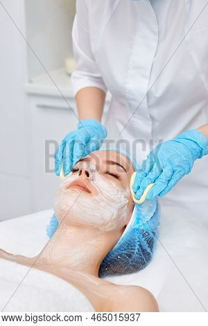 Beautician Cleanses Skin Of Beautiful Woman With A Sponge.
