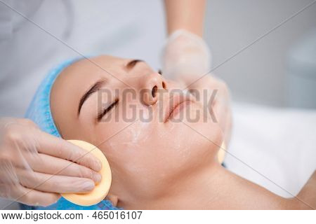 Beautician Cleanses Skin Of Beautiful Woman With A Sponge.